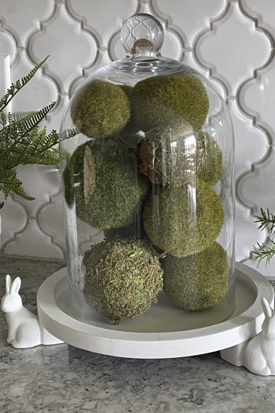 A cloche filled with moss balls sitting on a DIY bunny tray