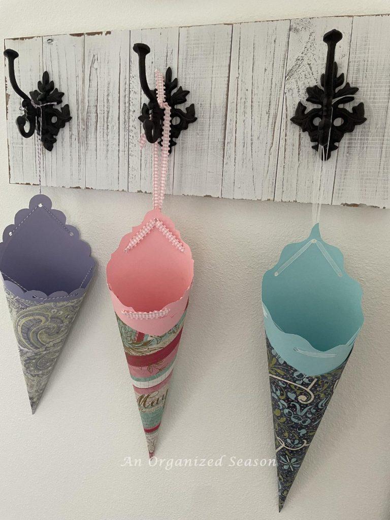 Three paper cones hanging on a coat rack. 