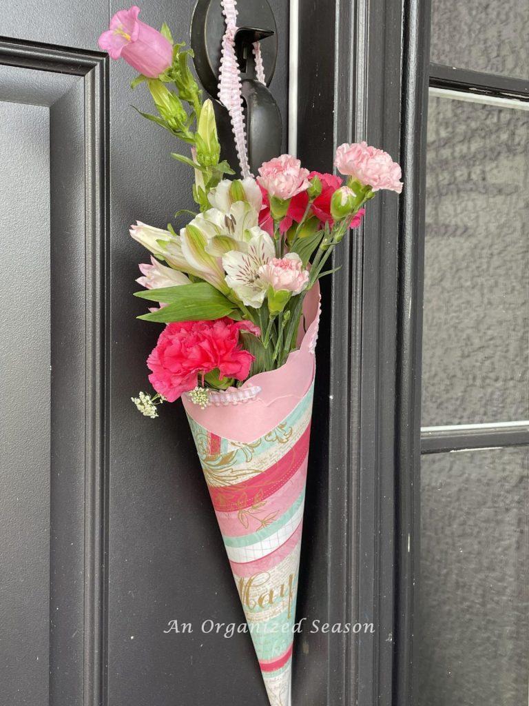 A pink May Day basket hanging on a front door.  