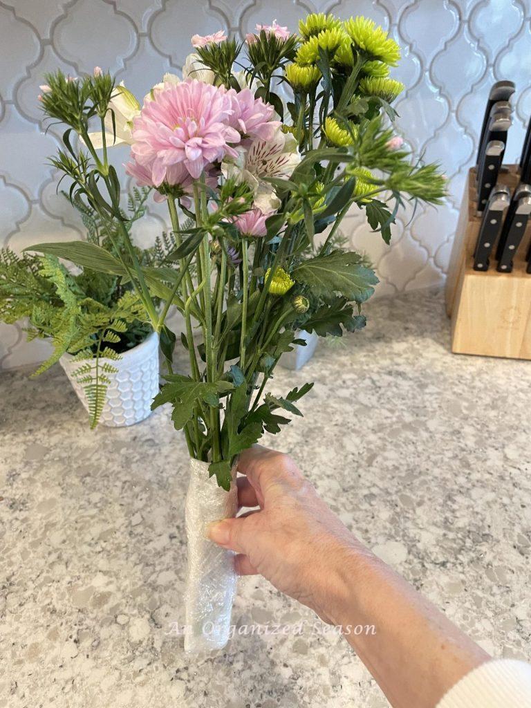 Flowers with a wet paper towel and plastic wrapped around the stems. 