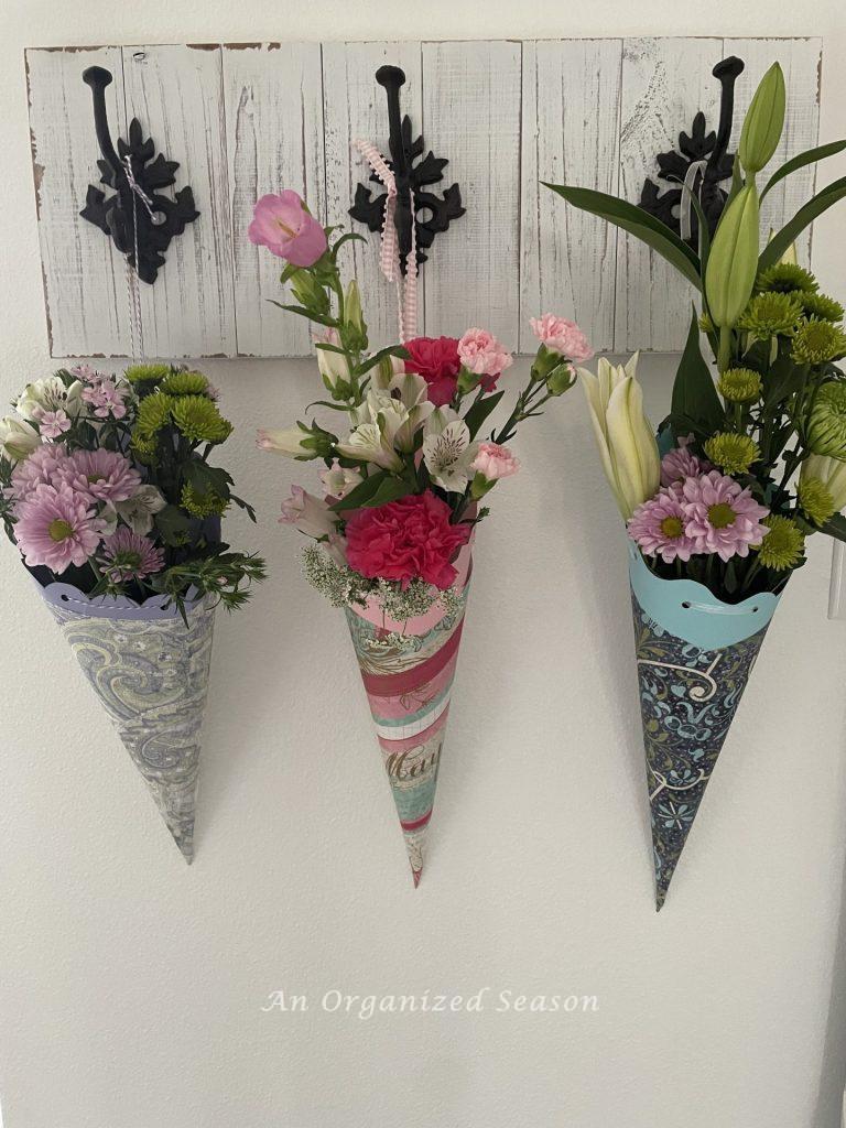 Three paper May Day baskets hanging on a coat rack. 