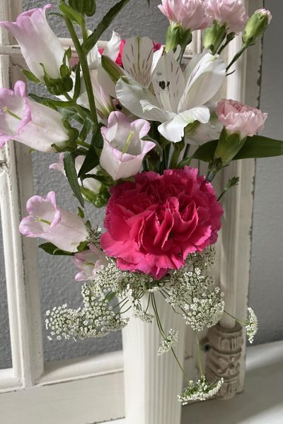 Pink and white flowers in a cream vase.