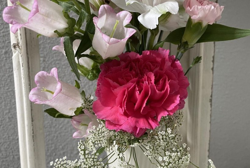 Pink and white flowers in a cream vase.