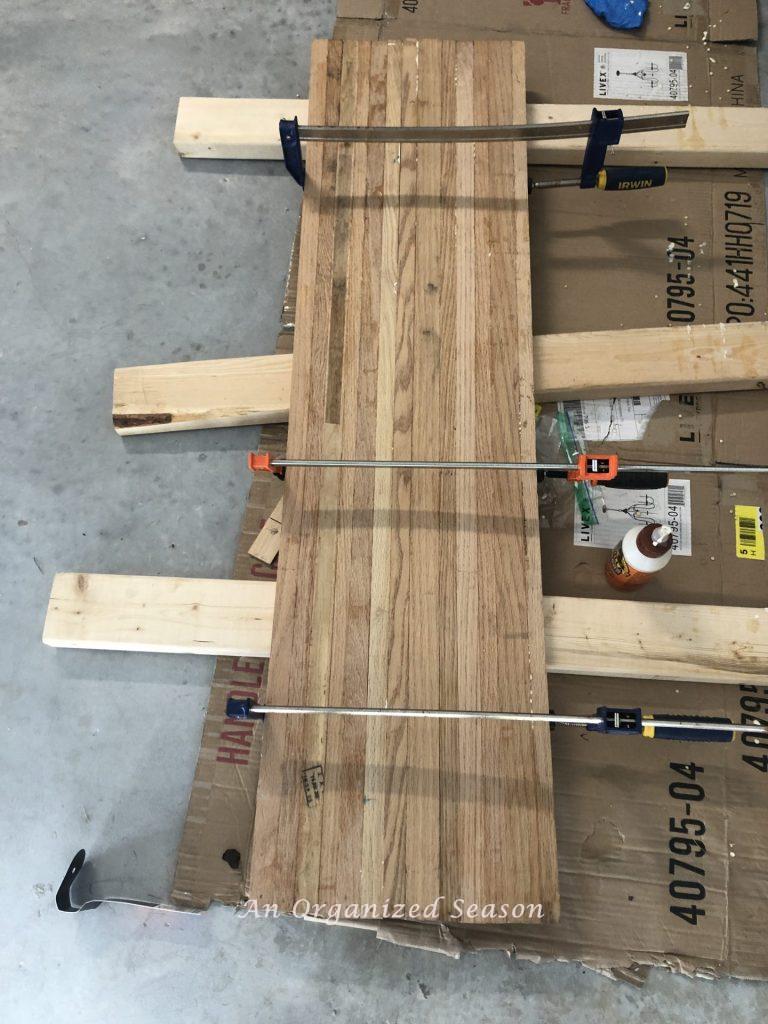 To make a DIY wood board, glue pieces of wood together and hold with bar clamps.