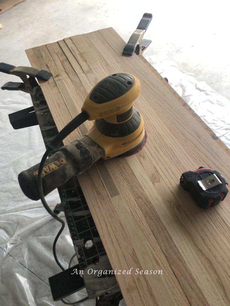 To make a DIY wood board, sand the glued boards until the top is smooth.