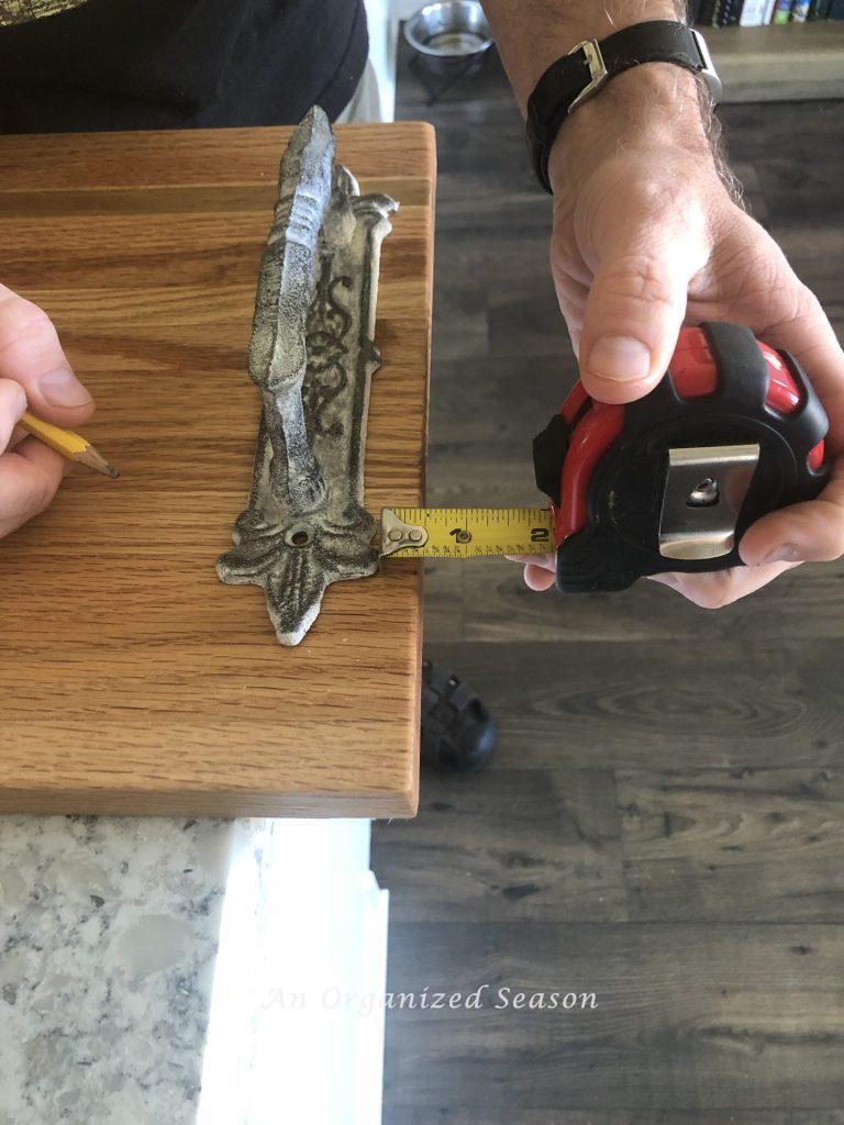 Man measuring the edge of a wood tray.