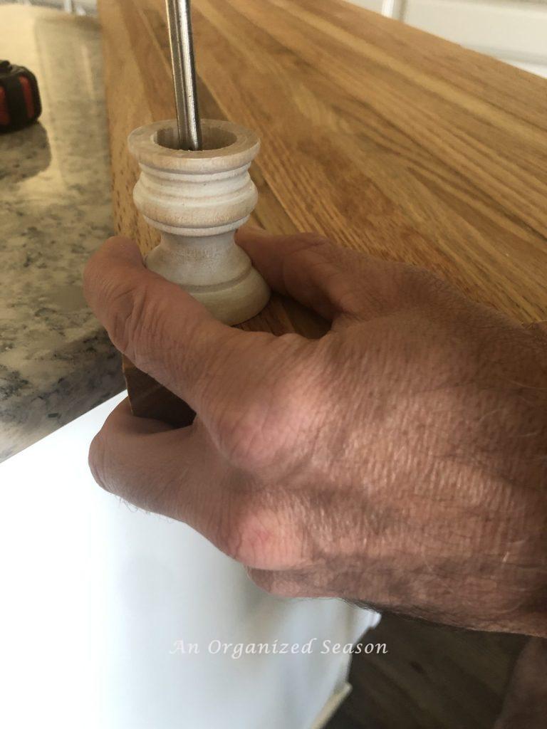 Man screwing a wood foot onto a tray.