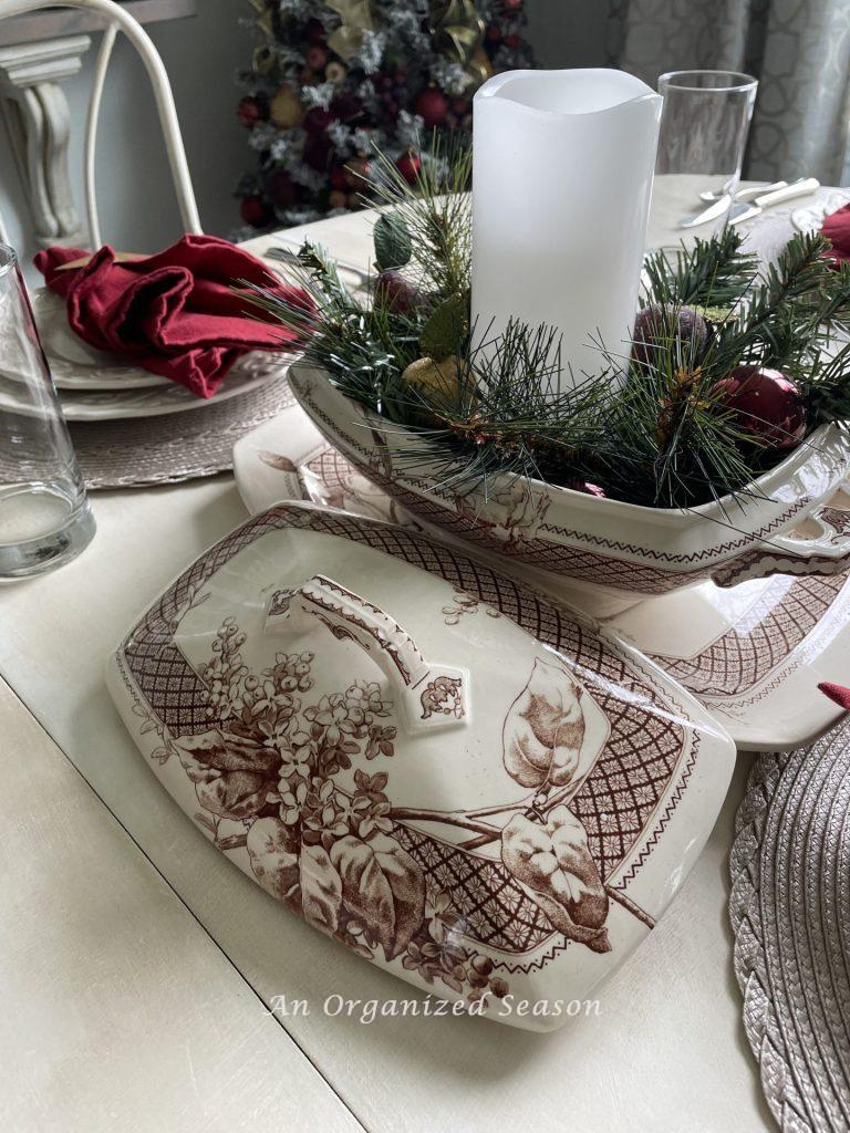 Brown transferware bowl holding a candle and greenery for a Christmas centerpiece. 
