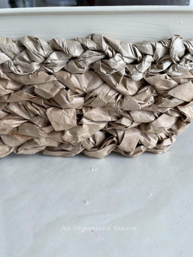 Brown packing paper braids wrapped around a tin. 
