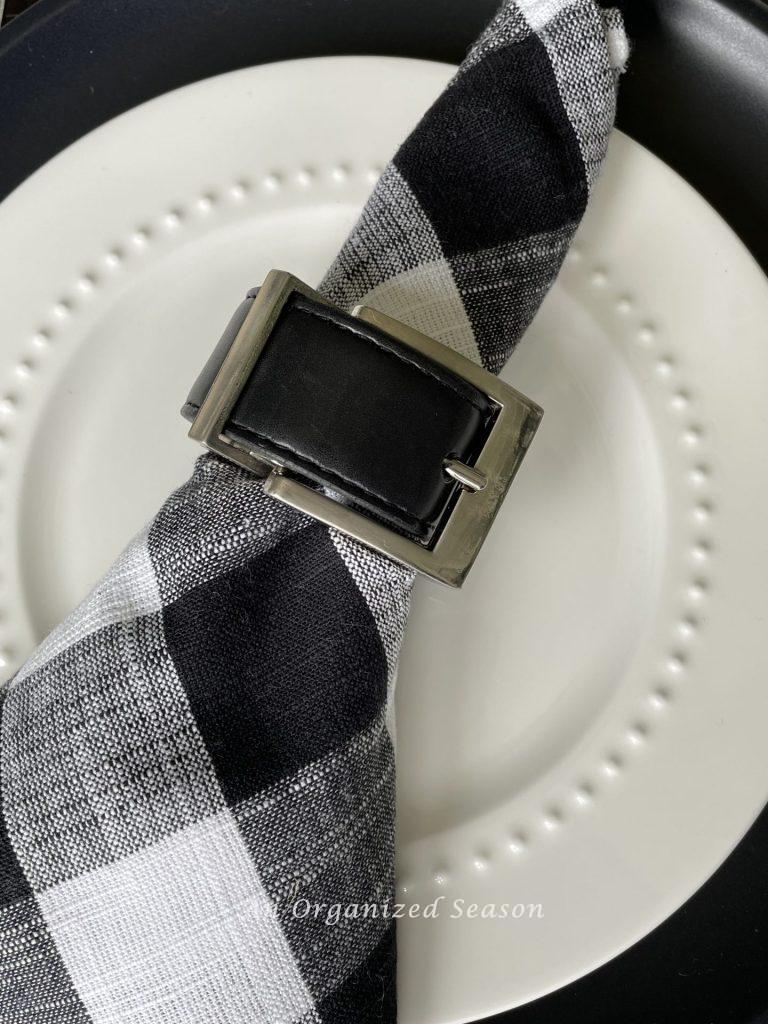 Leather belt napkin ring around a black and white buffalo check napkin are table decor for Father's day! 