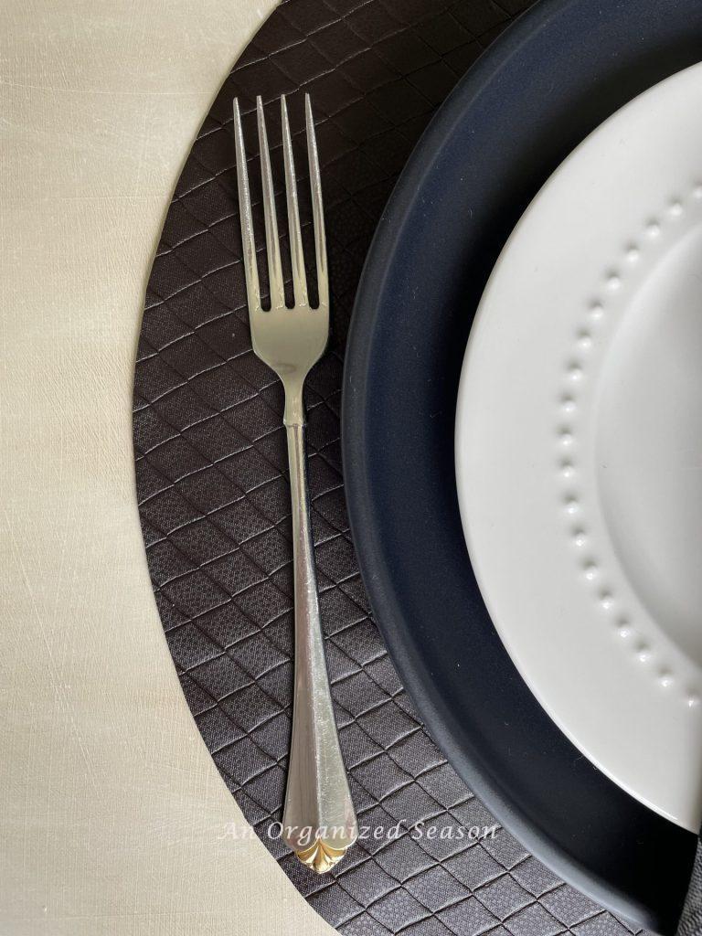 Brown leather placemat, black dinner plate, white salad plate, and fork are table decor for Father's day. 