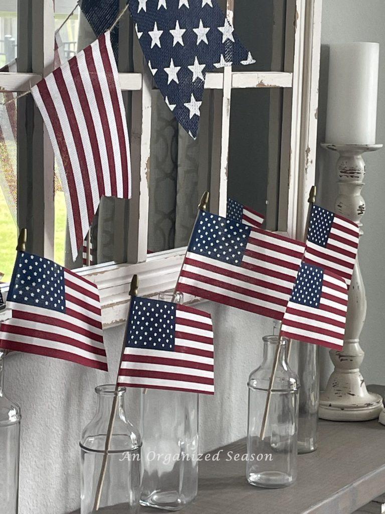 American flags in clear bottles sitting on a shelf. 