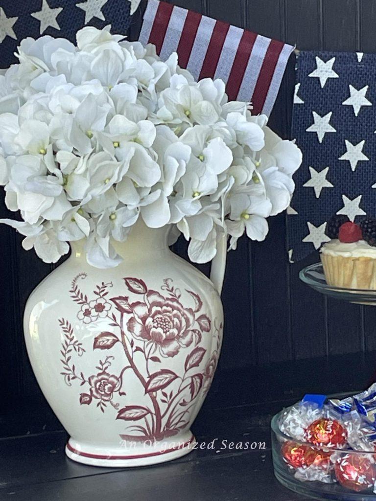 Patriotic idea number eight is to fill a red and white floral pitcher with white hydrangeas. 