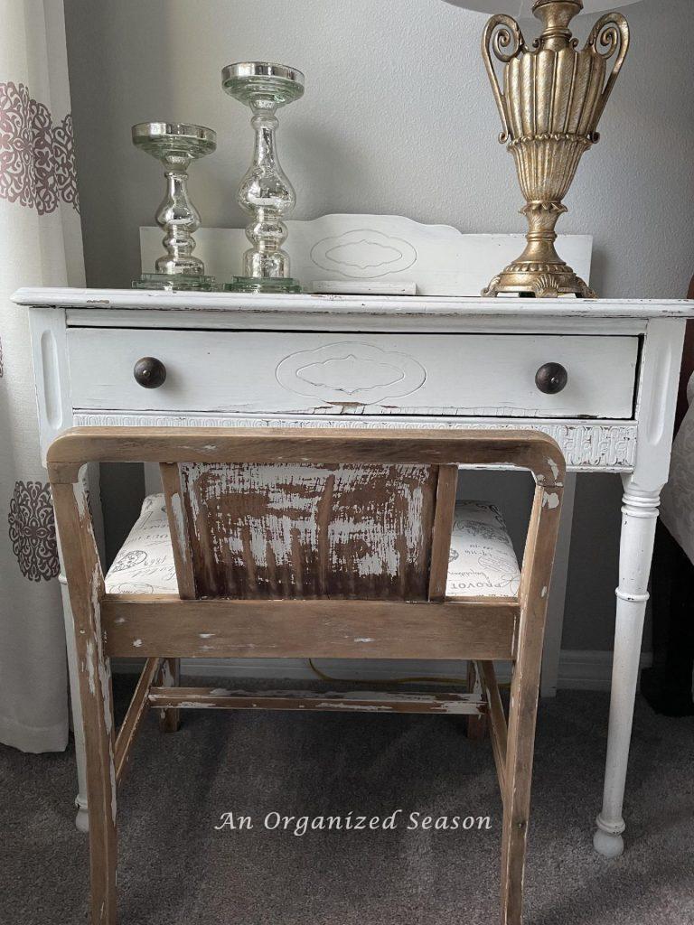 A white desk and stool with chipping paint. 