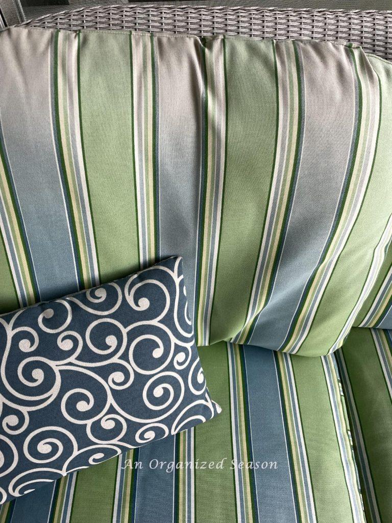 A striped outdoor couch cushion that is faded on the top. 