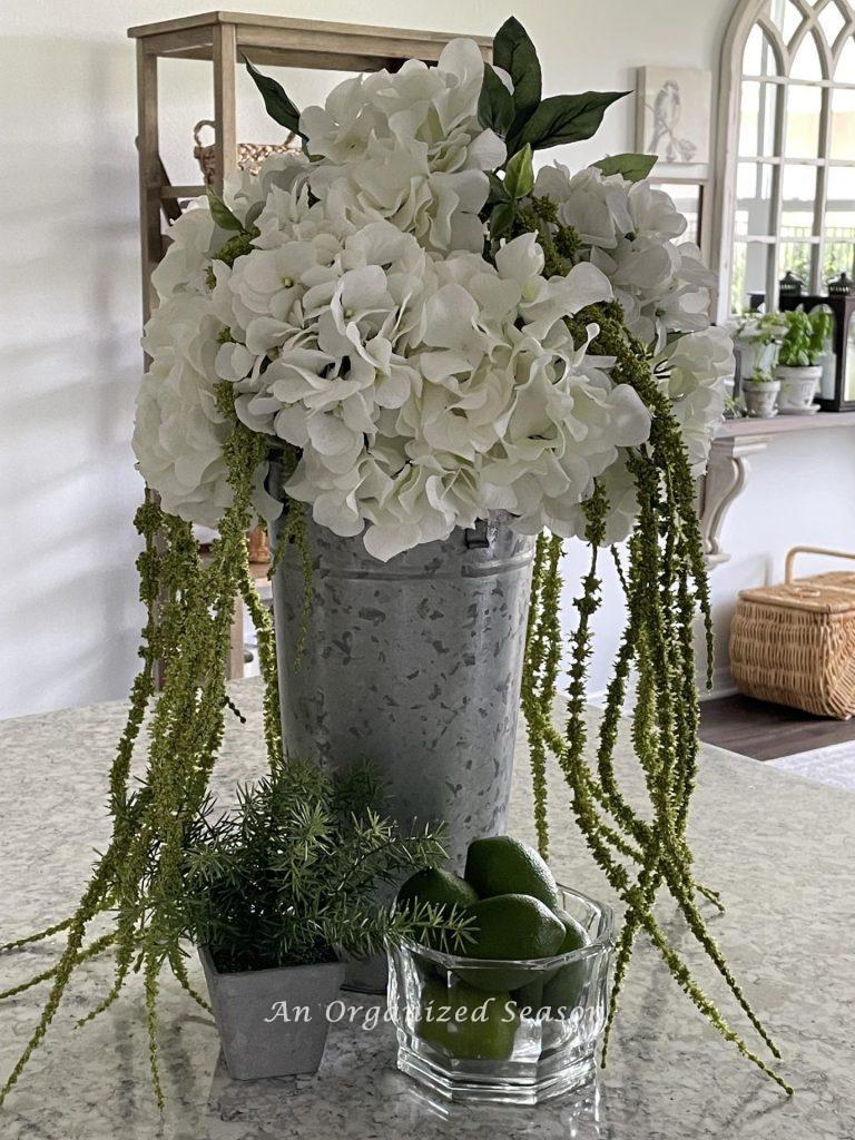 Summer decor tip #6, display a centerpiece of white hydrangeas in a tall galvanized container on a kitchen counter. 