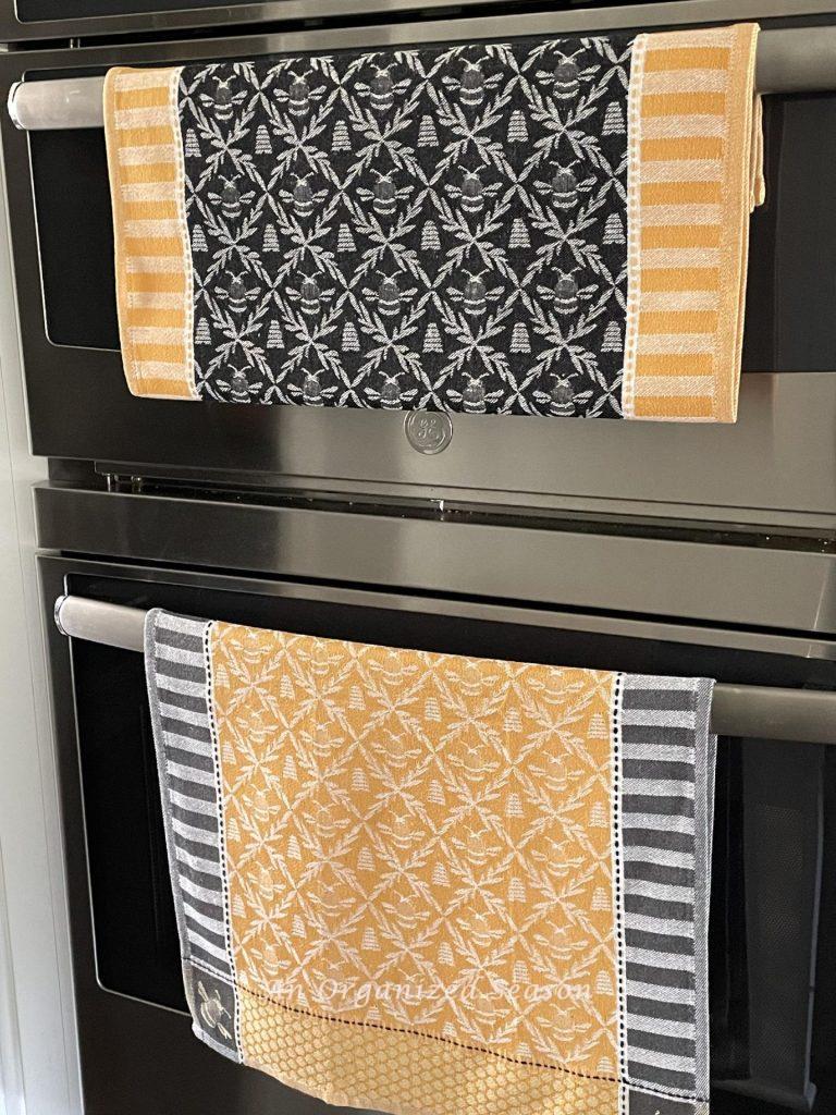 Summer decor tip #4, display gold and gray kitchen towels with bees on  oven and microwave doors.