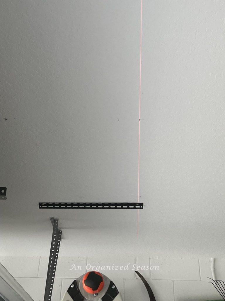 Laser level lined up on ceiling through screws on ceiling bracket