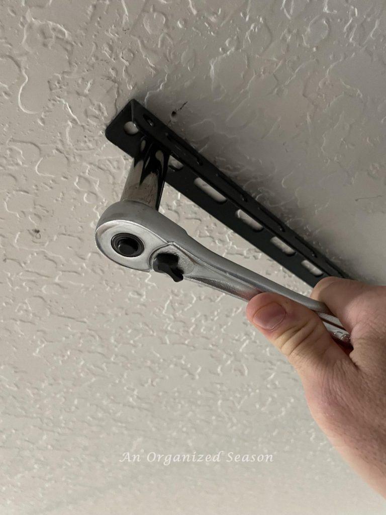 Man using ratchet to tighten bolts on ceiling bracket