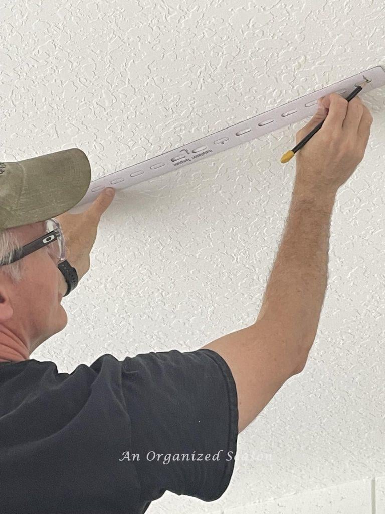 Step two to install overheard garage storage is to mark holes for brackets using manufacturers template.