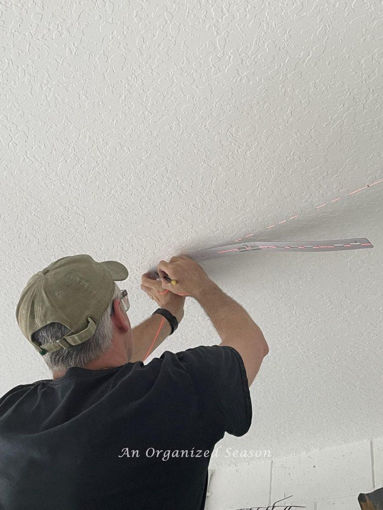 Man marking screw holes on ceiling using template