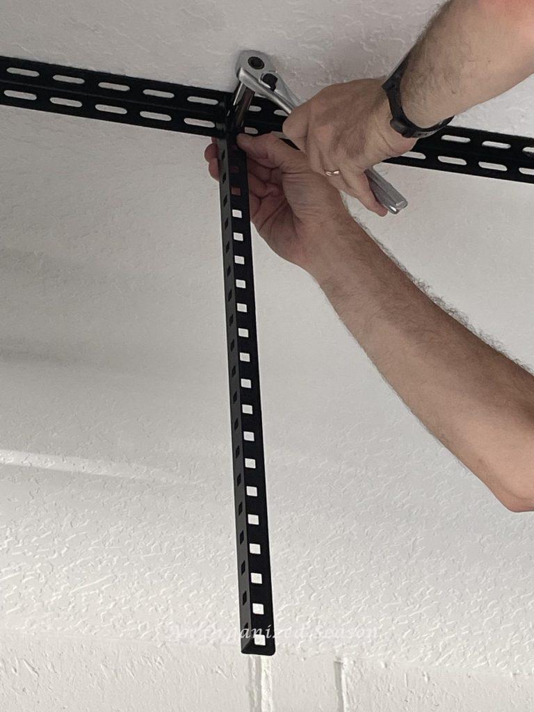 Man tightening bolts with ratchet to connect vertical support to ceiling bracket