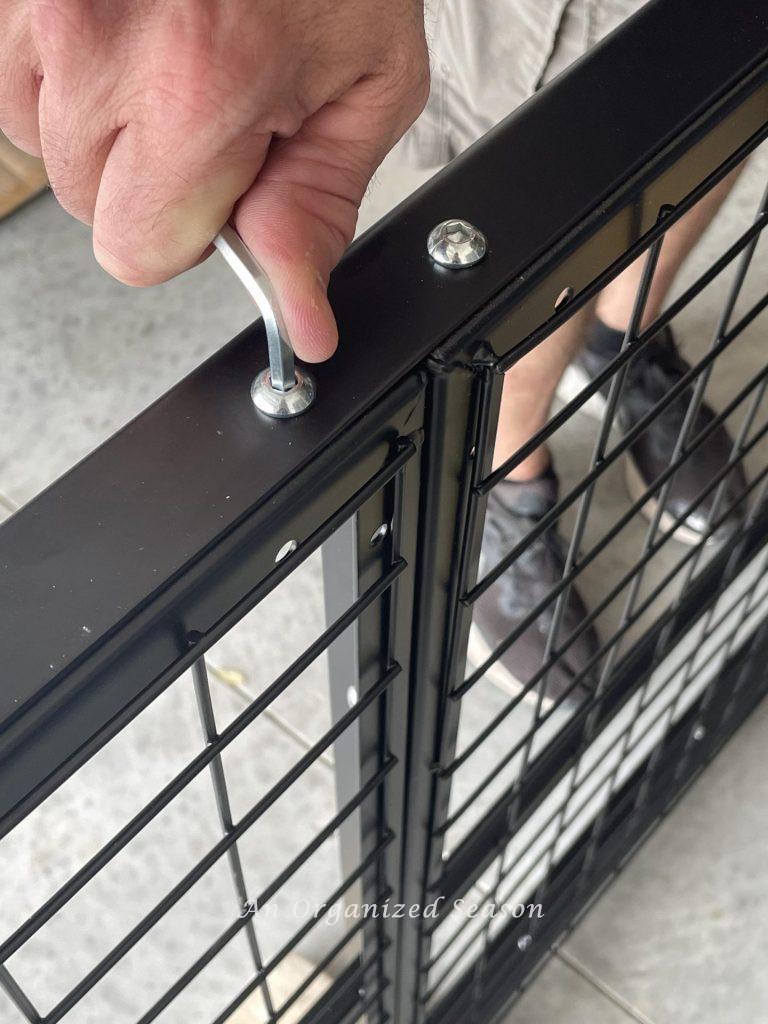 Hand using Allen wrench to tighten bolt on wire grid side bracket