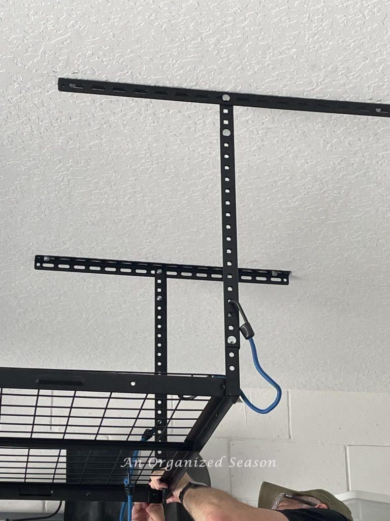 Man tightening bolts on end of wire grid shelf to vertical supports