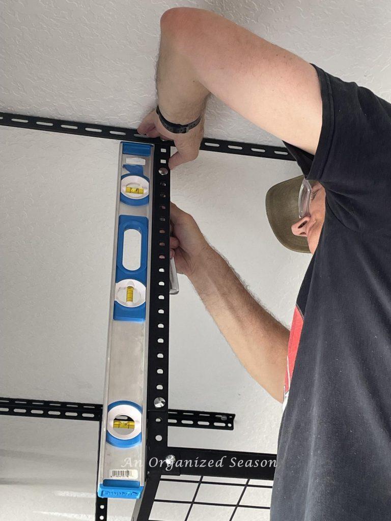 Man tightening bolts on vertical supports while using a level to ensure brackets are vertically straight