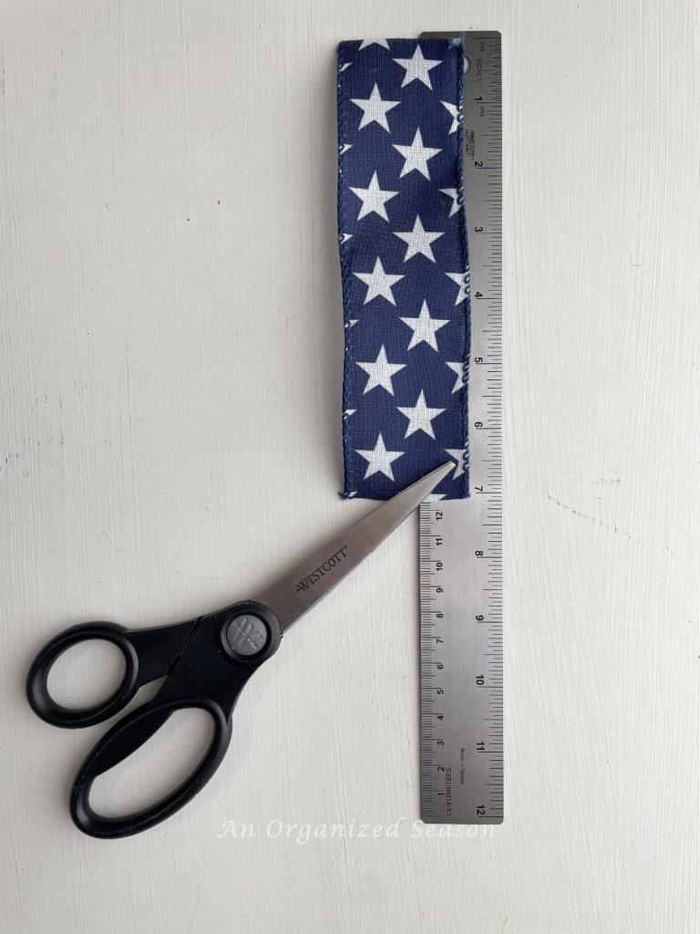 Measure blue and white star ribbon to 7 inches and cut with scissors  to make a DIY 4th of July wreath. 