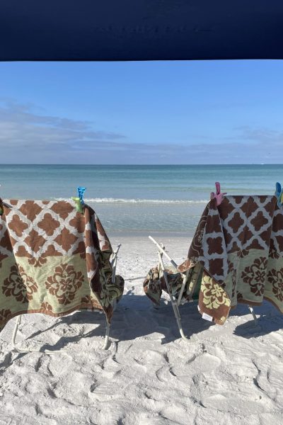 Two beach chairs covered in matching towels and sitting by the ocean.