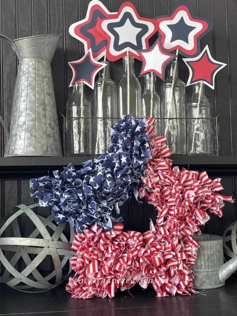 A patriotic star wreath in front of bottles holding red, white, and blue paper stars. 