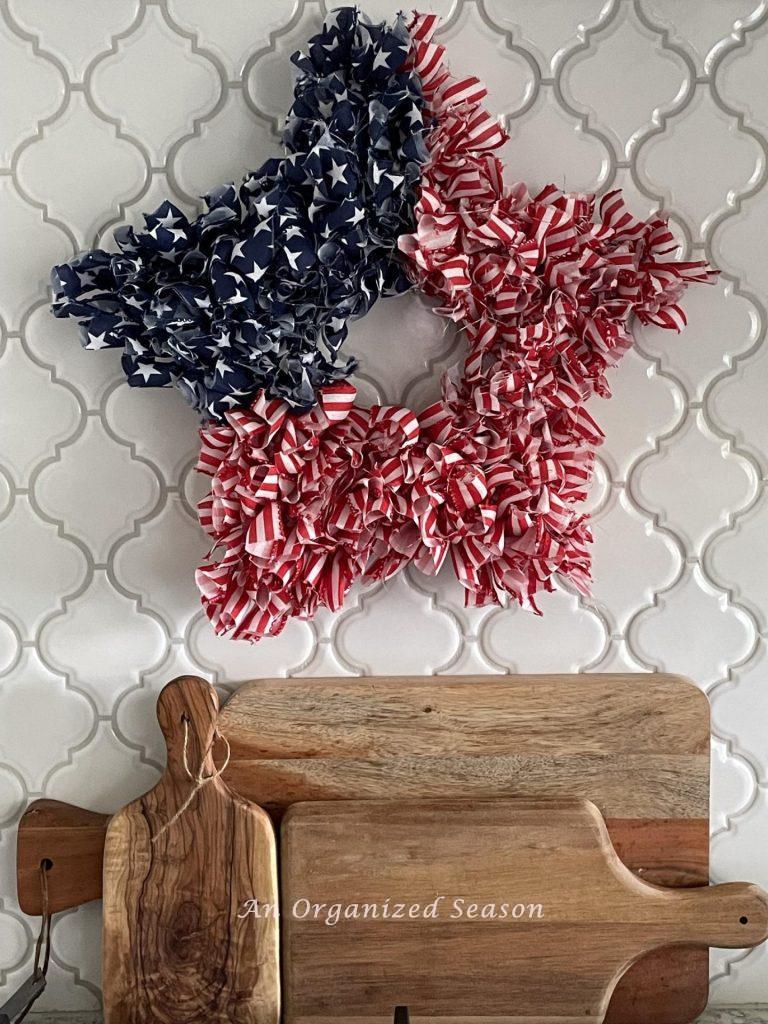 An American flag DIY ribbon wreath hanging on a kitchen backsplash. 