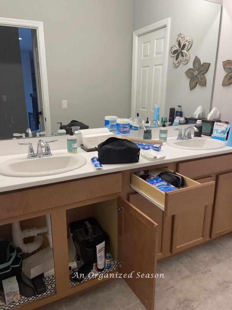 Cluttered bathroom counter, drawer, and cabinets that need to be organized.