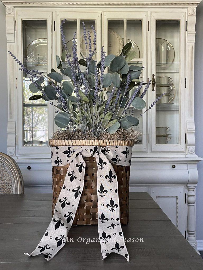 Step five to make a lavender wreath is to add a ribbon around the basket.