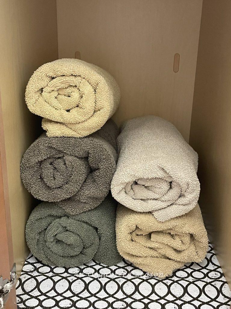 Organized rolled towels in a bathroom cabinet.