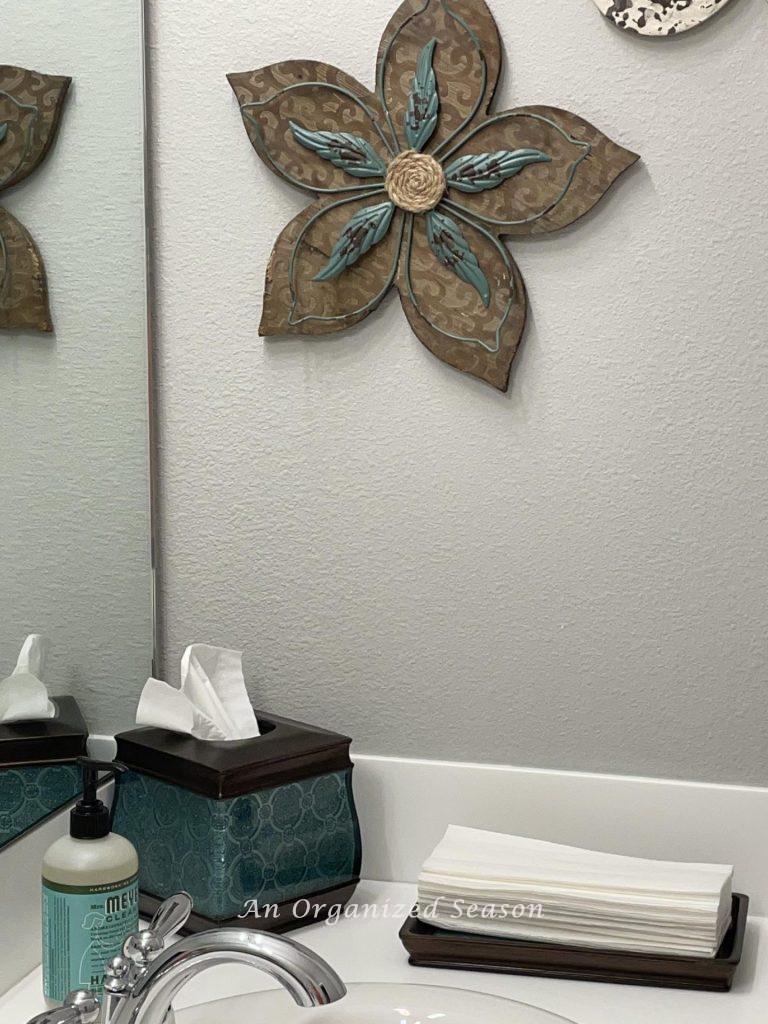 Tissue holder, hand soap, and paper towels on a tray sitting on a bathroom counter. 