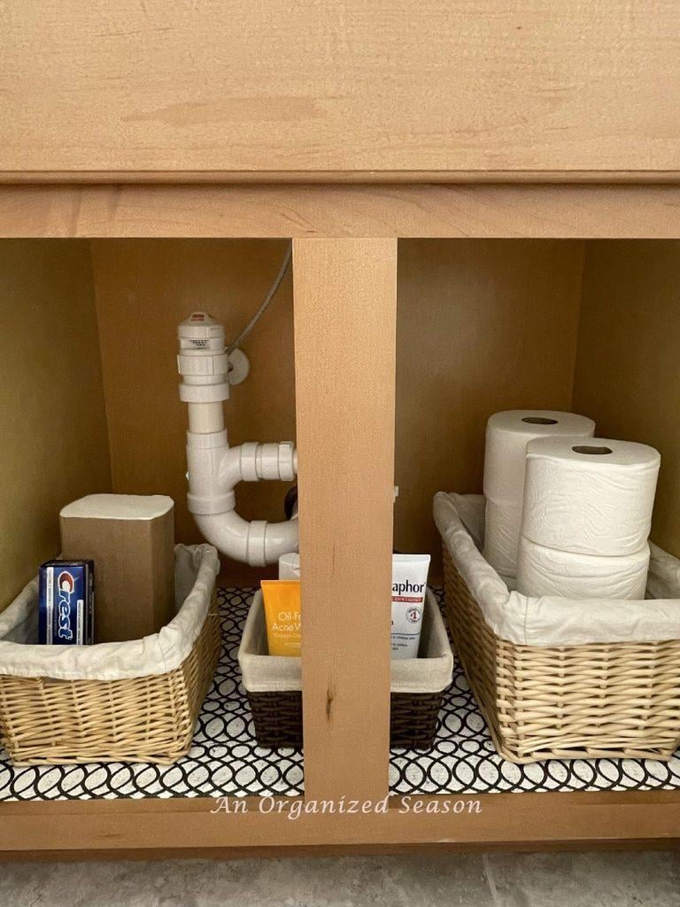 A bathroom cabinet organized with baskets.