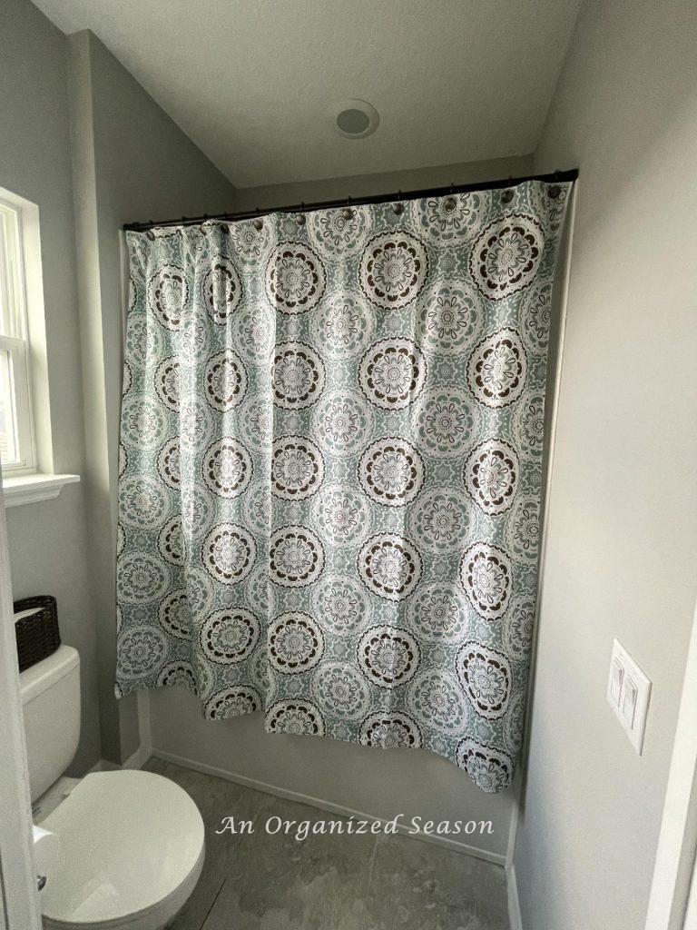 A shower curtain that is too short hanging in a bathroom.