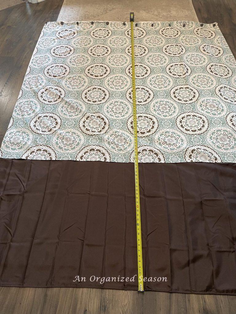 Measuring the length of two curtains on a floor.