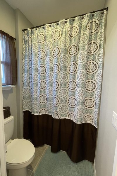 An extra long shower curtain hanging in bathroom.