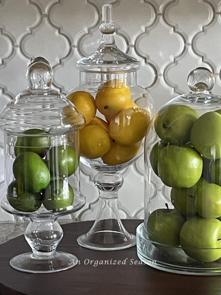 Three glass jars filled with fruit. The two apothecary jars are yard sale treasures. 