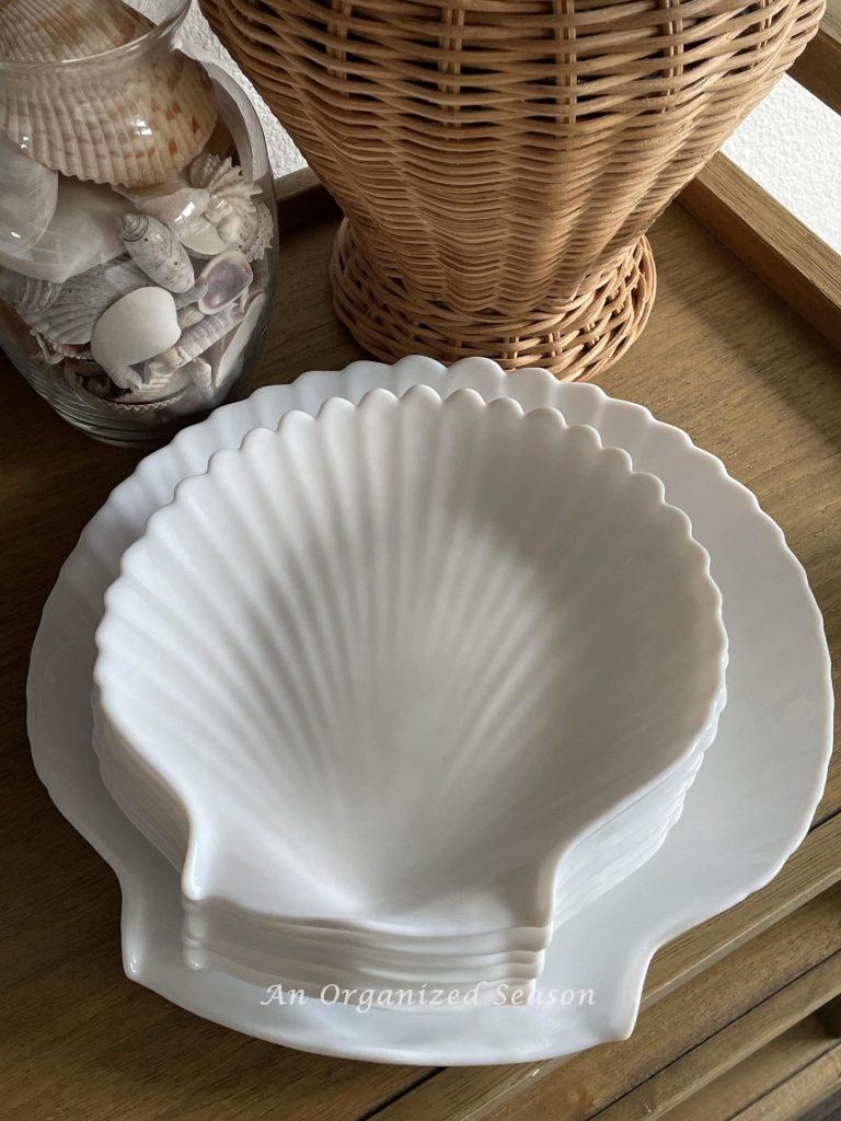 Six white plates and a platter shaped like a seashell.