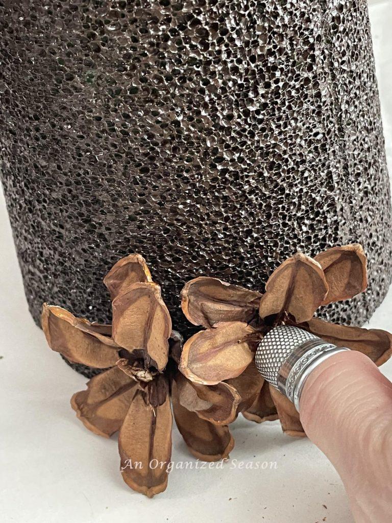 Step six is to push the pinecone flower into the cone with a thimble. 