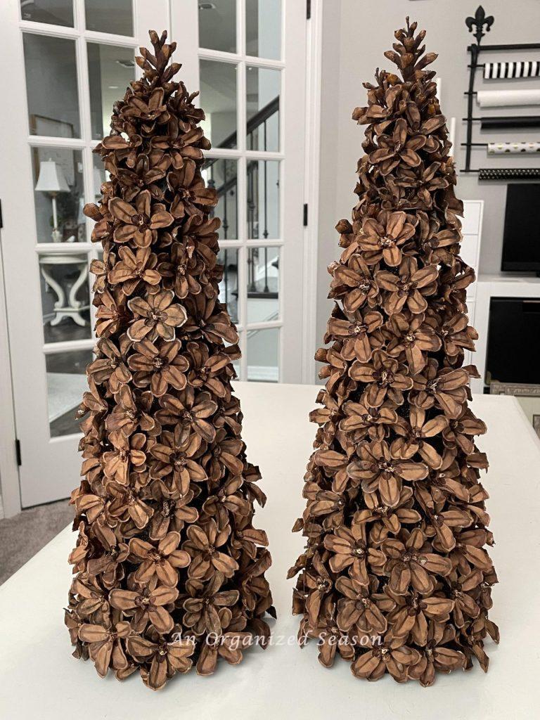 Two pinecone flower Christmas trees sitting on a table. 