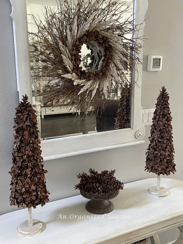 Two pinecone Christmas trees and a stand with pinecones sitting on a table. 