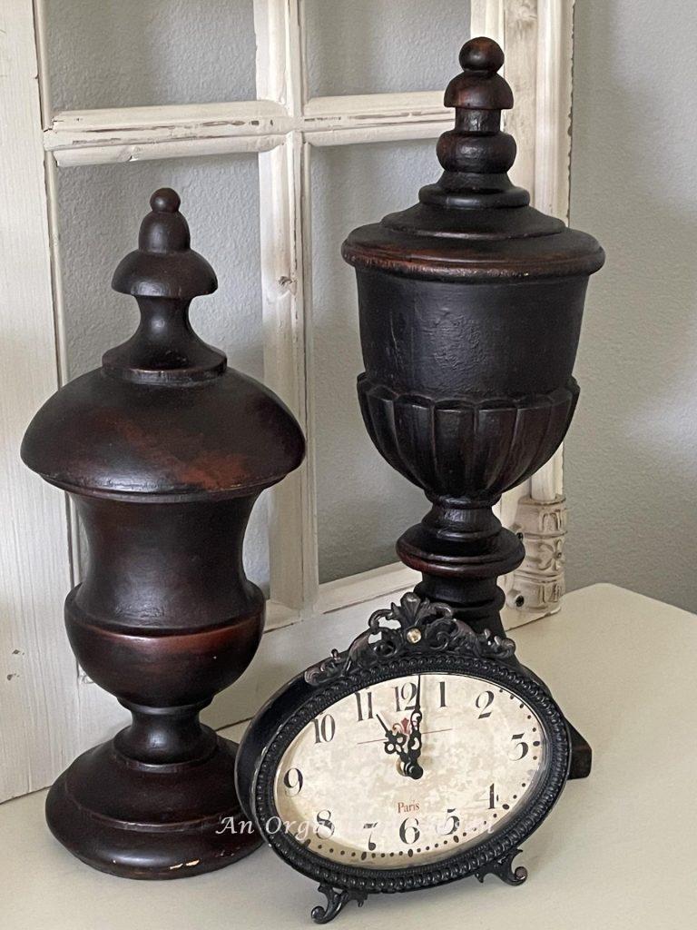 A clock showing 11 pm bedtime for a nighttime routine and two decorative wood finials on a nightstand. 