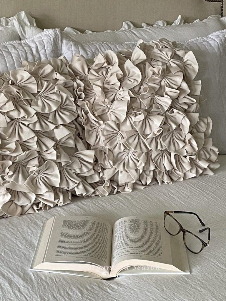 A book and a pair of glasses sitting on a bed. 