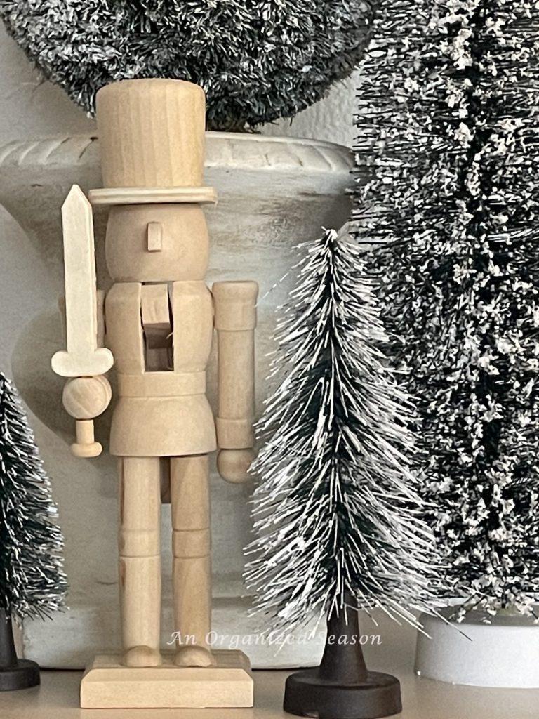 A nutcracker beside faux  cone Christmas trees. 