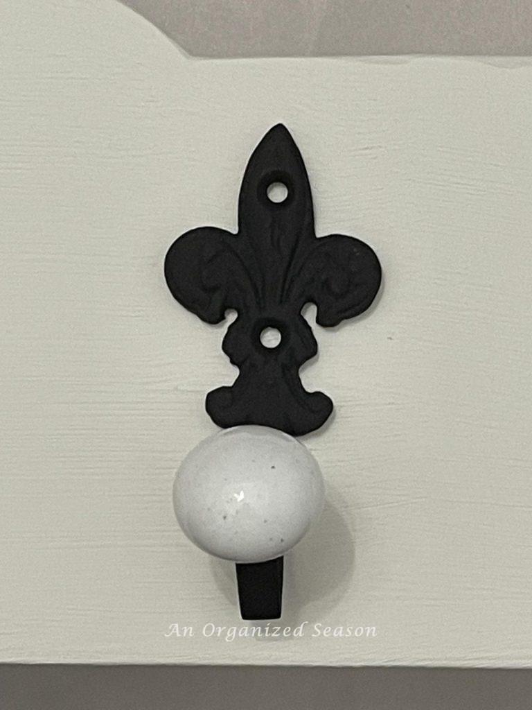 A fleur di lis towel hook painted black. 